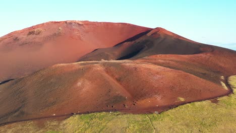 vista aérea del vibrante cono volcánico rojo westman en islandia, con hierba verde en contraste en su base