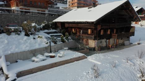 drone flying away from a warm hot tub and revealing a vacation home in a small swiss town in winter