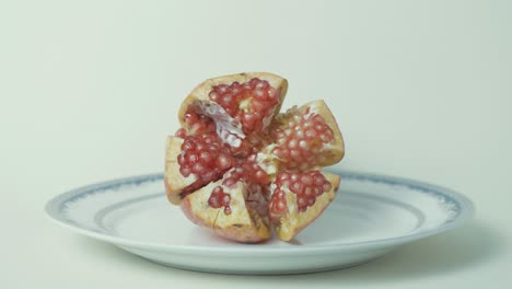 open pomegranate on plate delicious red seeds, static 4k shot