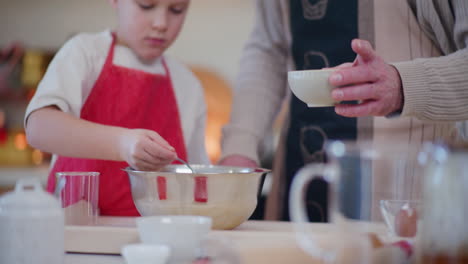 young boy pours cocoa into bowl and mixes ingredients