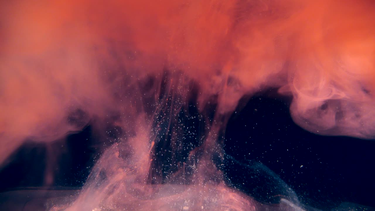 humo transparente rojo que se levanta desde abajo haciendo nubes de vapor sobre un fondo negro.