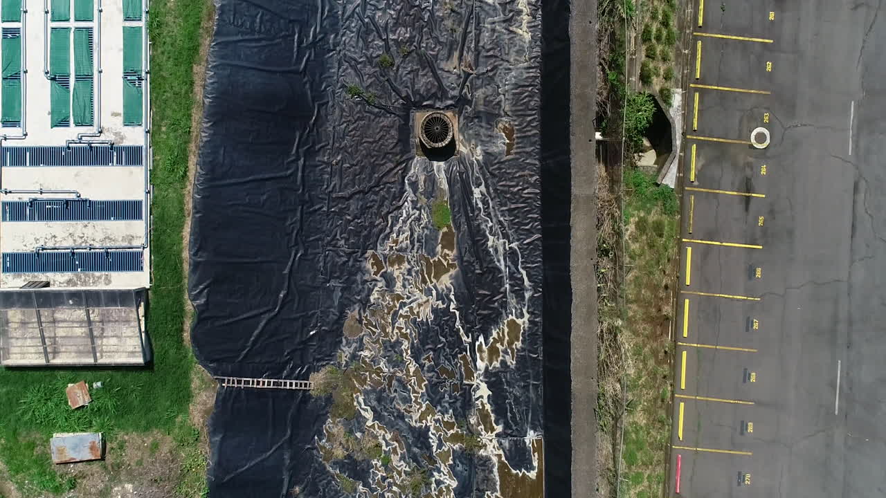 video aéreo de planta de tratamiento de aguas residuales, estanque de retención residencial junto al estacionamiento.