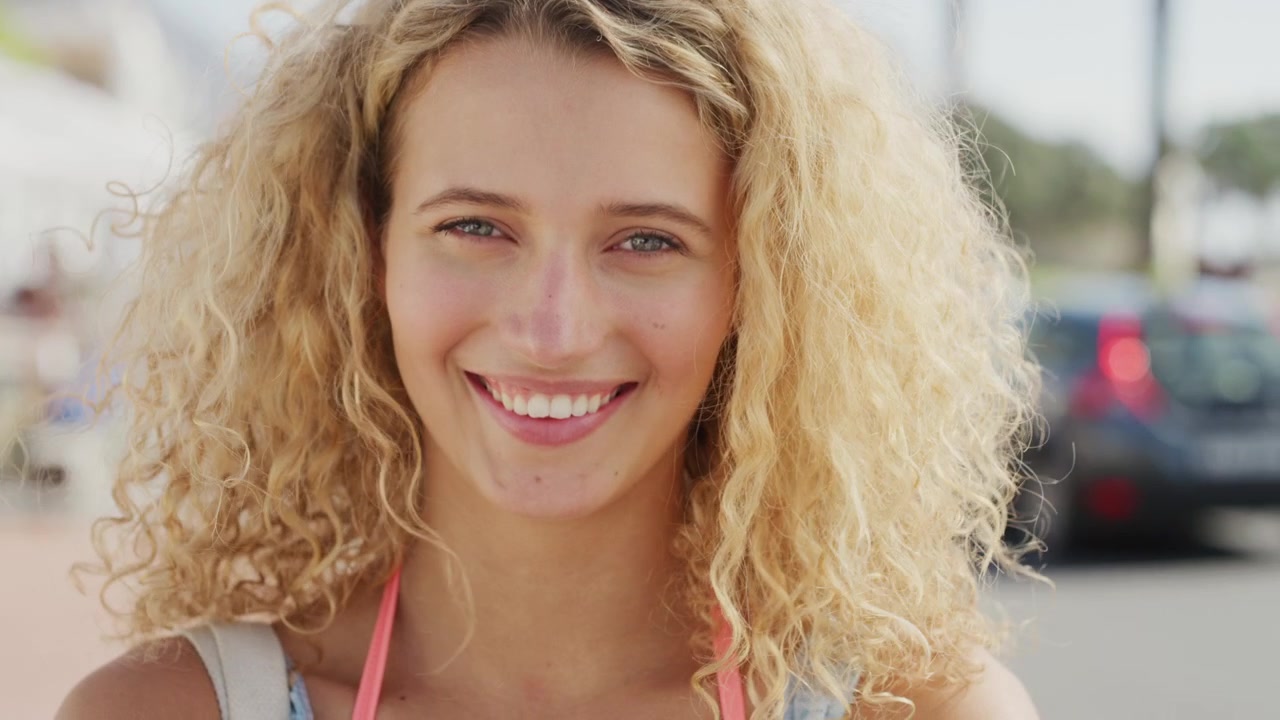 Portret van een lachende jonge vrouw met krullend blond haar
