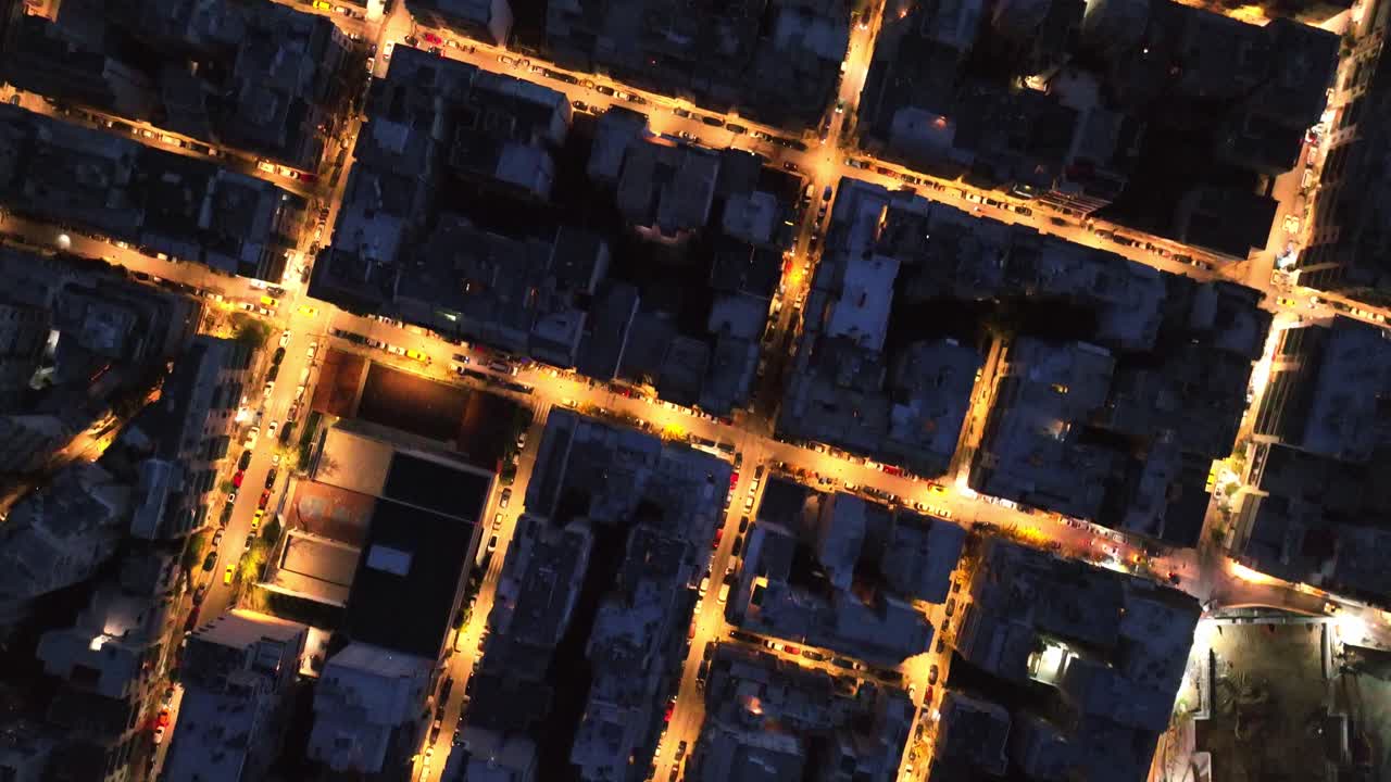Vue aérienne en plongée des rues de la ville illuminées la nuit.