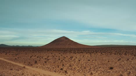 flying towards a volcanic cone mountain in the mojave desert's rocky terrain