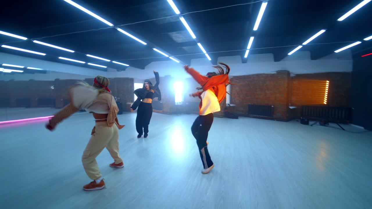 Girls trio dancing hip hop in the big spacious studio. Stylish energetic young dancers in the club.