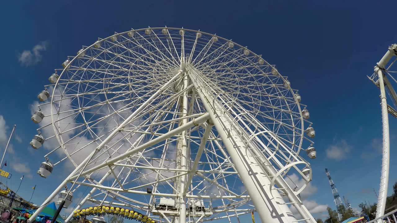 거대한 페리스 이 놀이 공원에서 파란 하늘 위에 높이 서 있습니다.