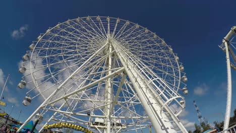 una rueda gigante se alza en el cielo azul en un parque de atracciones