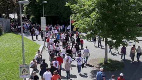 large crowd of people walking towards a stadium