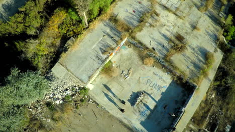 Toma-Aérea-De-Adolescentes-En-Patineta-En-La-Base-Cubierta-De-Graffiti-De-Un-Edificio-Abandonado-6