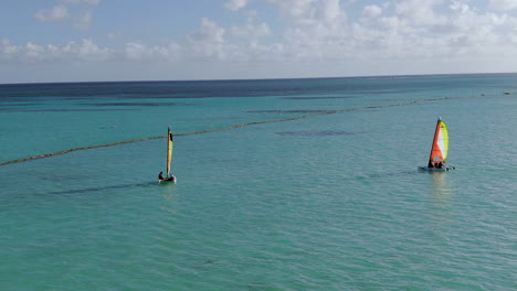 two catamarans sailing in tropical ocean, caribbean sea watersports and fun at beach