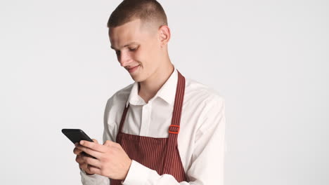 smiling blond waiter chatting with his smartphone