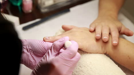 técnico de uñas que elimina las cutículas de las uñas de los clientes