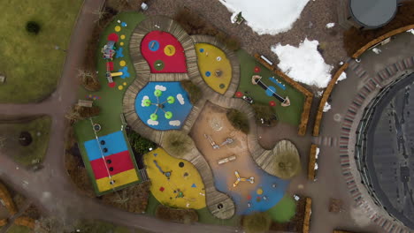 aerial rotating view high above colorful play park with winter snow