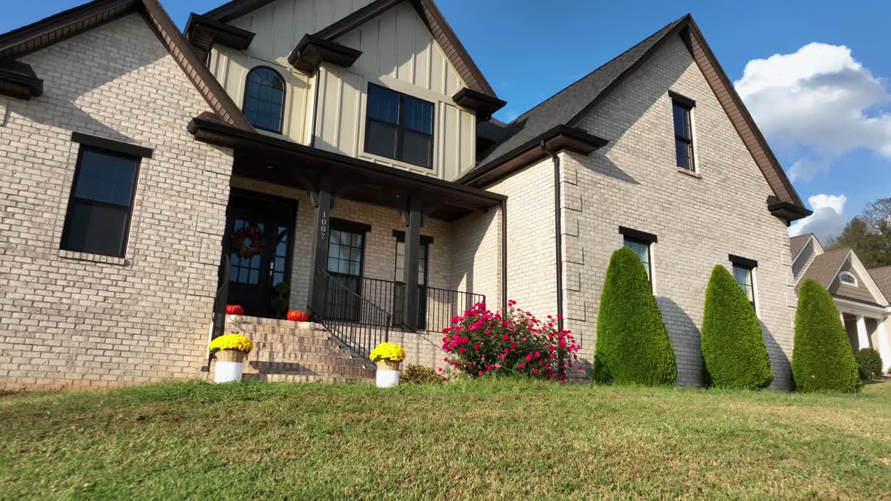 Modern American suburban home with brick facade, landscaped yard and bright flowers. Sunny summer day in USA. Comfort, style and contemporary neighborhood living