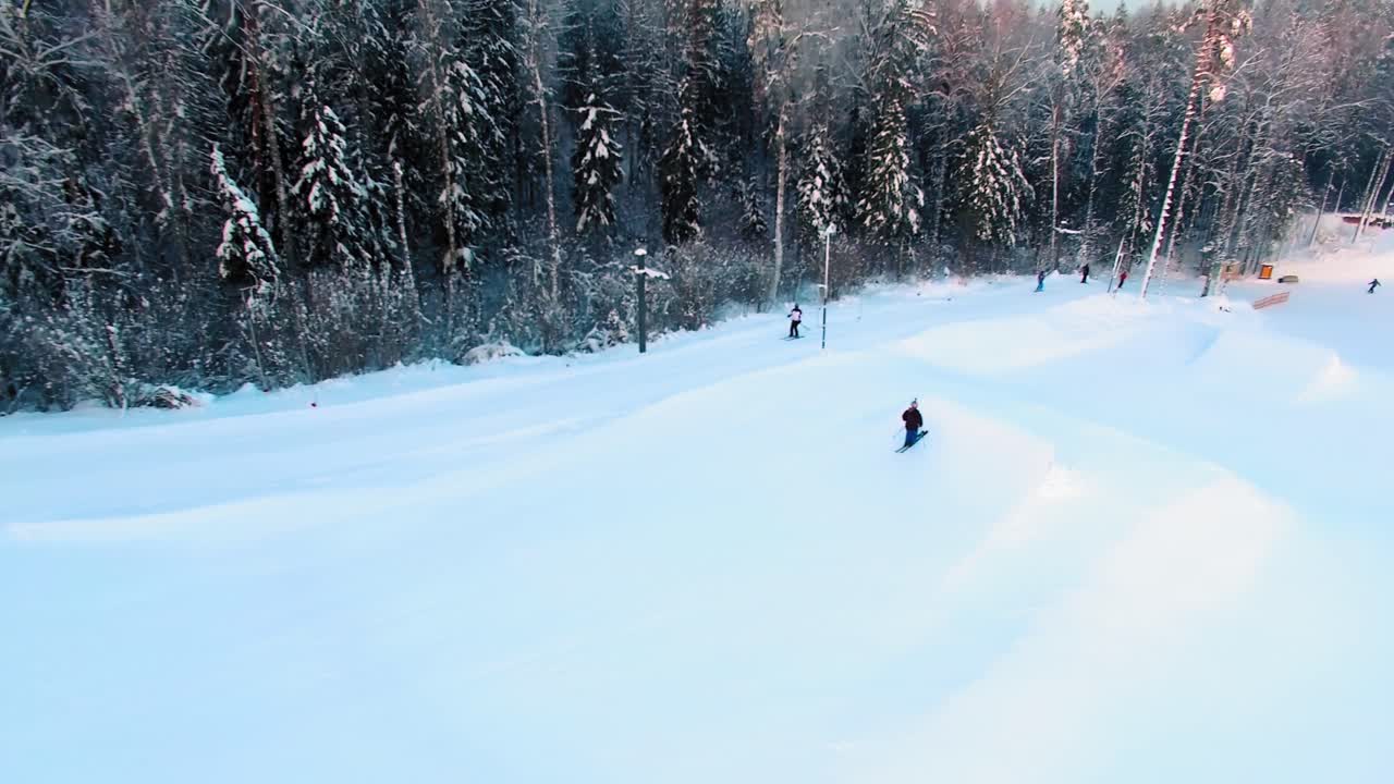 Side aerial view of a skier jumping off a slope in a terrain park