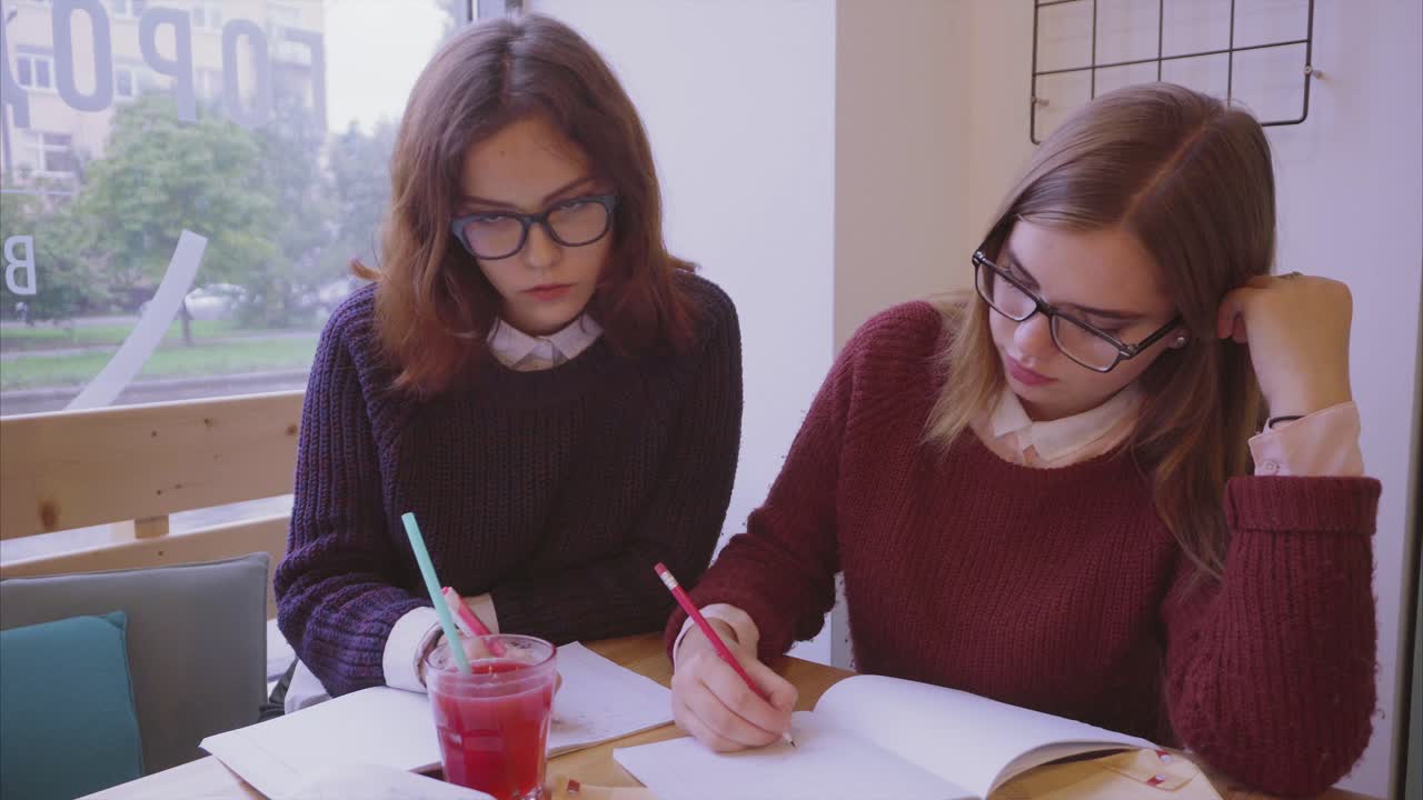 dos mujeres jóvenes estudiando en un café