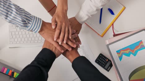 hands of different nationalities, skin colors, stacked one on top of the other over the office desk, an agreement, a close-knit team, working together, a bet, all for one