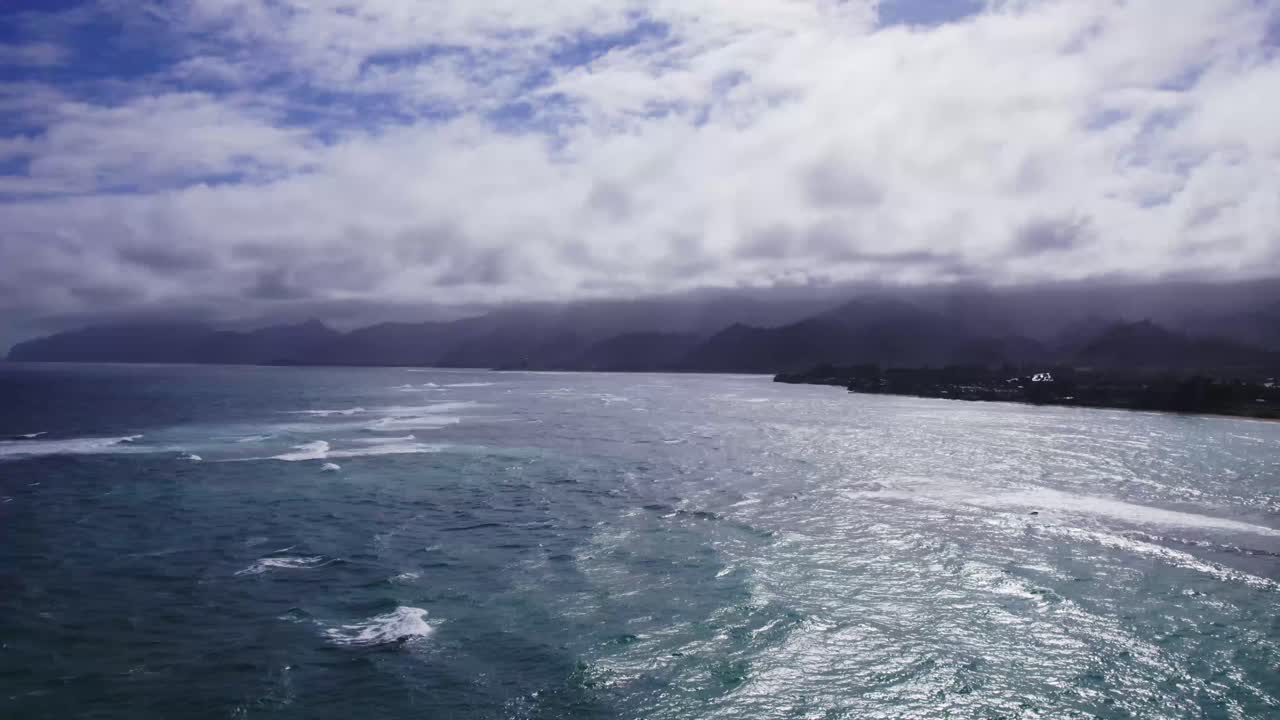 una vista aérea temprano en la mañana de una costa tranquila con olas suaves y cielos nublados