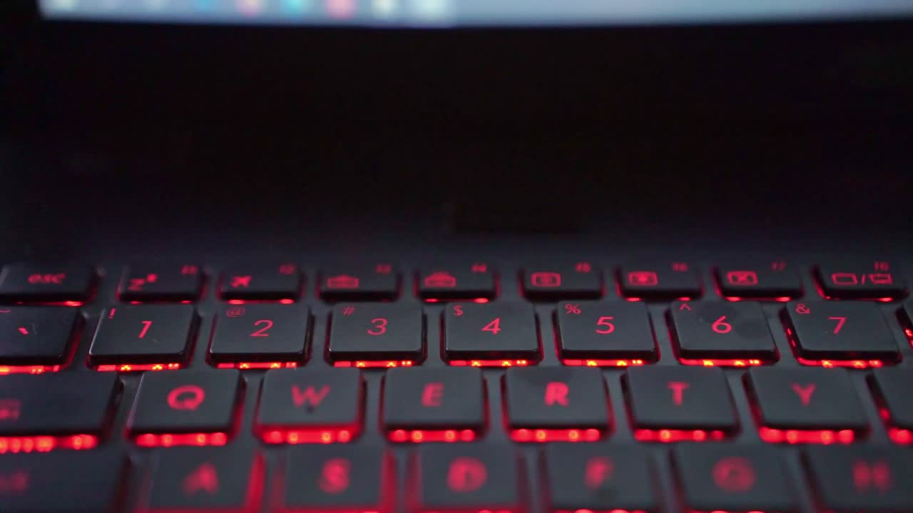 Typing hands on number laptop keyboard with LED lighting, programming and productivity concept