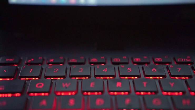 Tastende hænder på et numerisk tastatur på en bærbar computer med LED-belysning, et koncept for programmering og produktivitet.