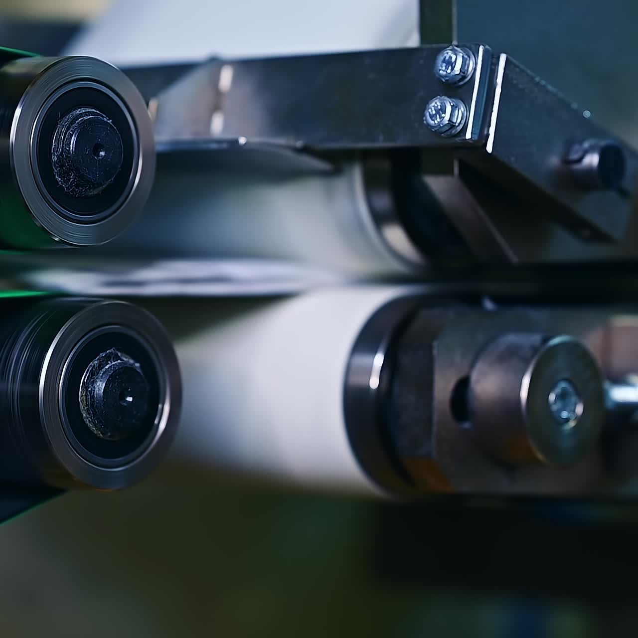 Technological process of diaper producing at the factory. Two stainless steel rollers rotating with non-woven cloth between. Close up