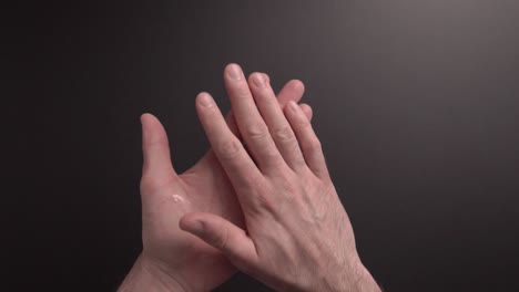 a man is sanitising his hand with hand sanitising gel in slow motion part1. dark background. plenty of space for text. great video for educational purposes
