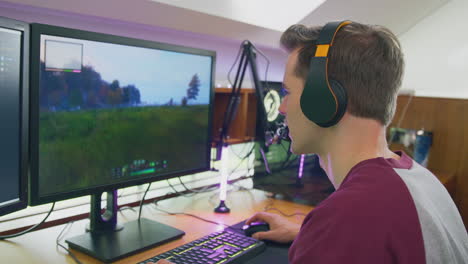 man gaming at home sitting at desk wearing headphones for live stream