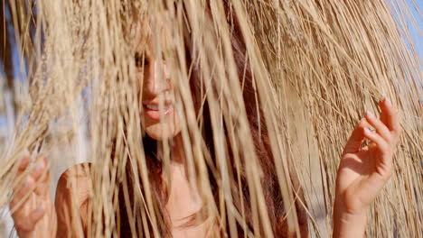 una mujer sexy escondiéndose detrás de un paraguas de playa.
