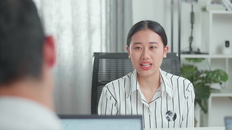 An Asian Woman Interviewee Sitting On The Chair And Answering The Questions Be Asked By A Businessman During Interviewing At The Office