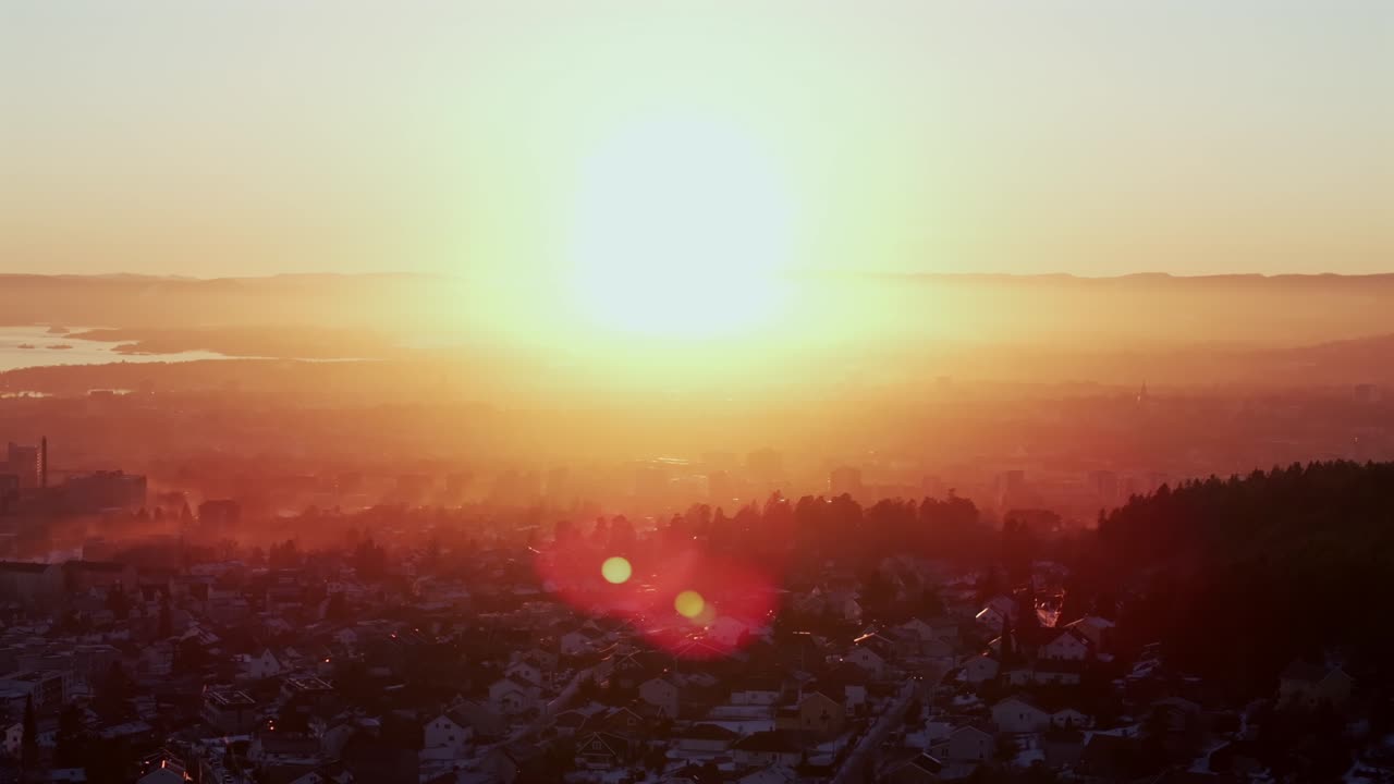 Artic winter vibrant sunset Olso Norway Norge aerial drone sun on horizon golden hour downtown Oslofjord city view Holmenkollen Holmenkollbakken Ski Jump Skimore Skisenter home buildings circle right