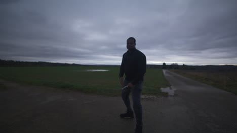 Modern-Black-Swordsman-Warrior-Awaiting-Battle-Opponent-in-Open-Field-Under-Grey-Sky,-Europe,-4K-|-Muscular,-Intimidating,-Shadow,-Figure,-Blurry,-Dark-Clothes,-Powerful,-Dramatic,-Tense,-Stance