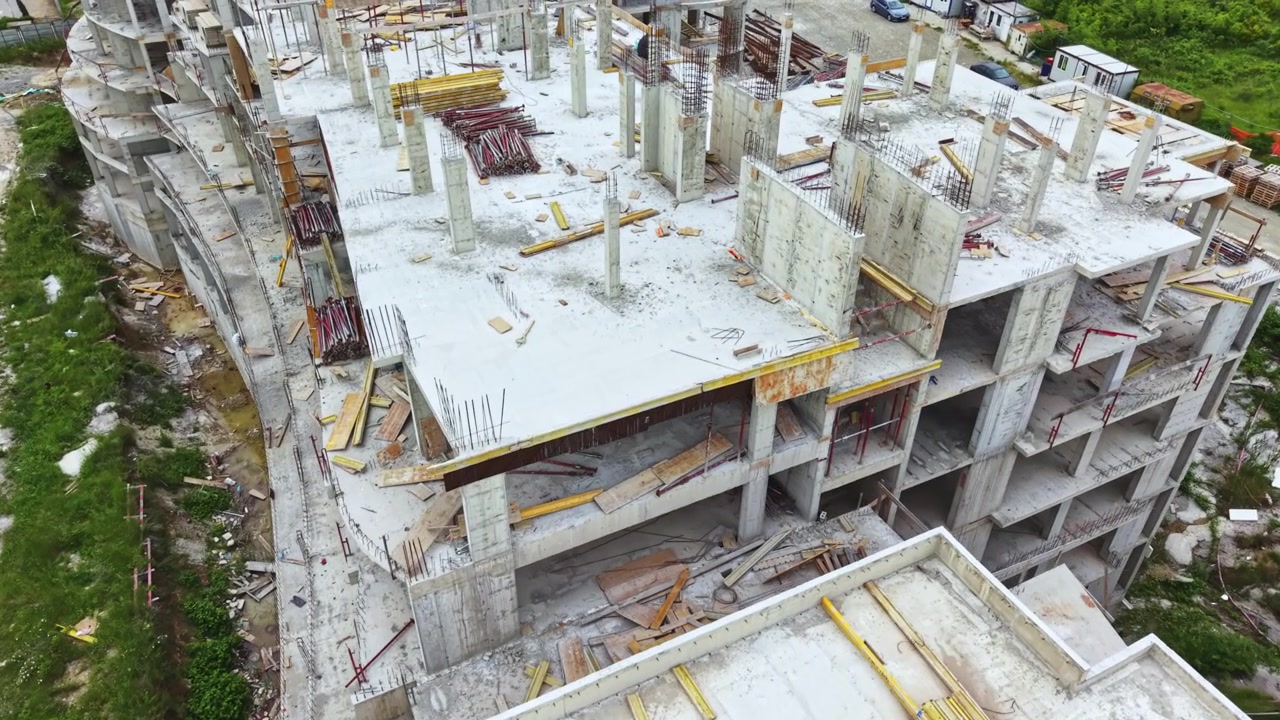 Construction site of a large building with unfinished structure and materials located in an urban area during a cloudy day