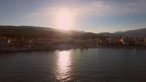 Aerial:-Small-fishing-town-with-Greek-flag-on-Samos-island,-Greece