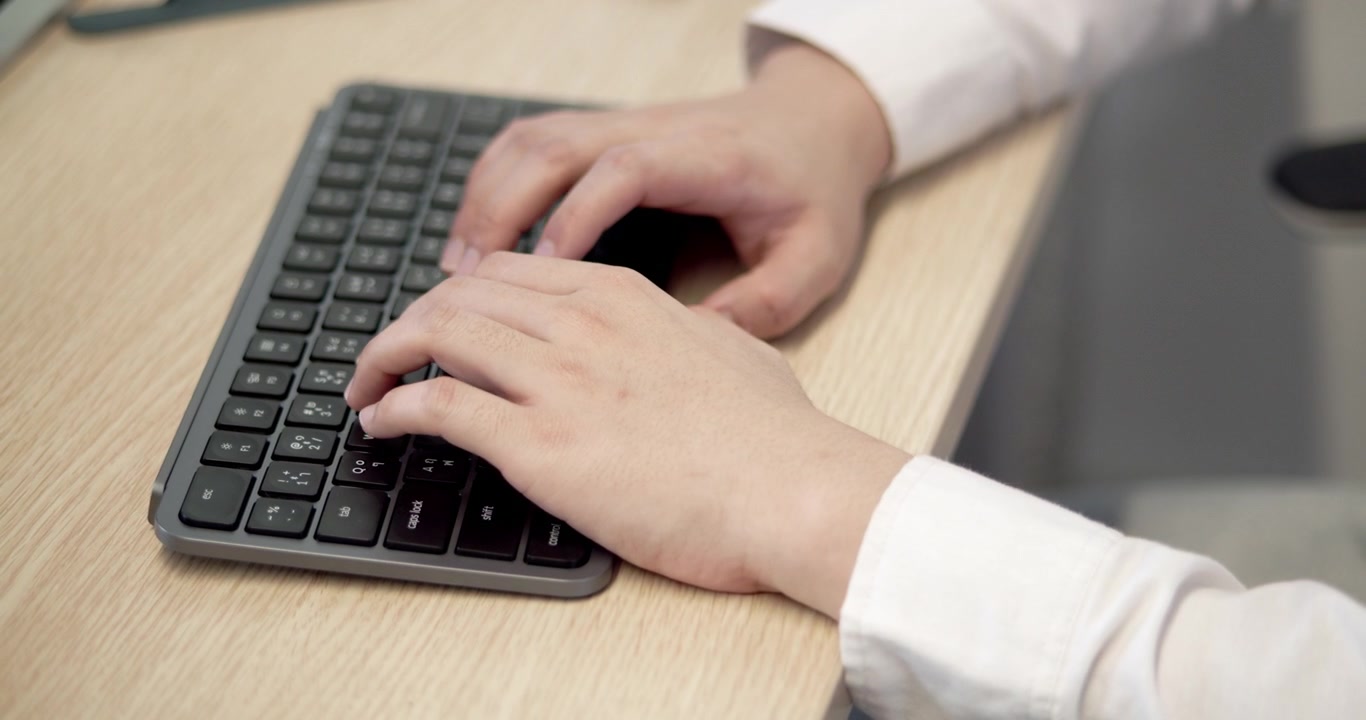 Una vista ravvicinata di mani che digitano su una tastiera, mostrando un ambiente d'ufficio professionale.
