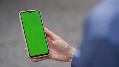 arm holding green mobile phone in office closeup. manager videocalling partner