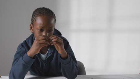 Studio-Shot-Of-Boy-At-Table-Struggling-To-Concentrate-On-School-Book-4