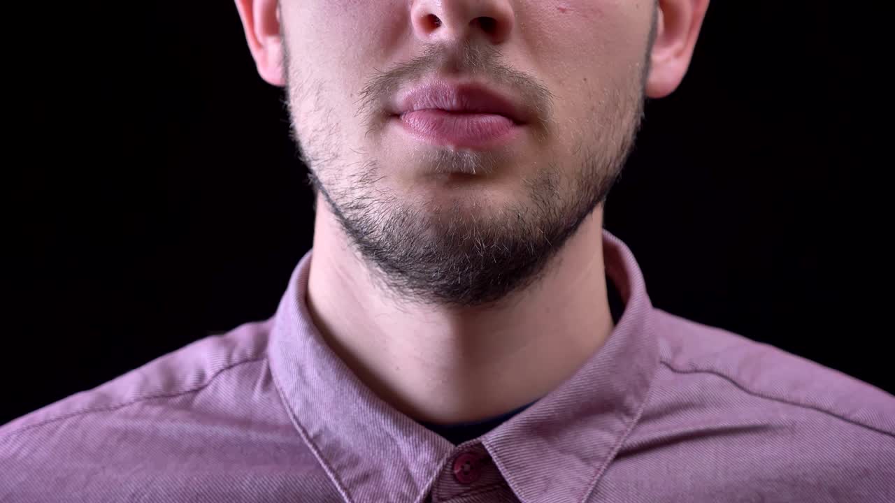 retrato en primer plano de un hombre que muestra una deliciosa rosquilla esmaltada con patatas fritas multicolores y ojos sobre un fondo negro.