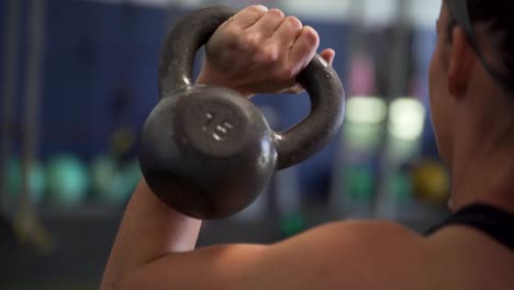 mujer haciendo sentadillas con campana en el gimnasio