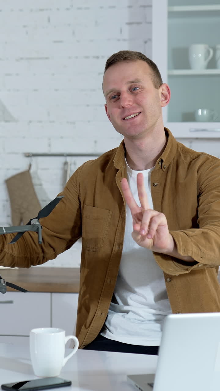 Kyiv, Ukraine, 2 May 2025: Male tutor showing drone. Young man showing drone for shooting video at home. Vertical video