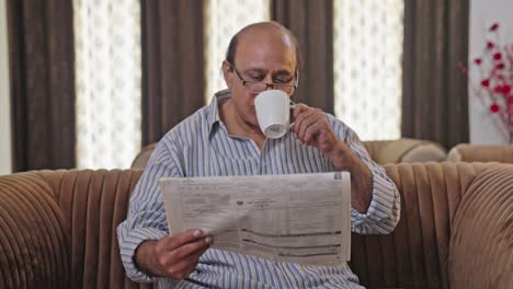 happy indian old man reading newspaper