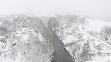 aerial view overlooking a river stream and a lake on a snowy day in sweden