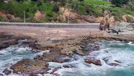 Ein-Fischer-Bereitet-Seine-Ausrüstung-Auf-Den-Nassen-Felsen-An-Einem-Strand-In-Wollongong-Vor