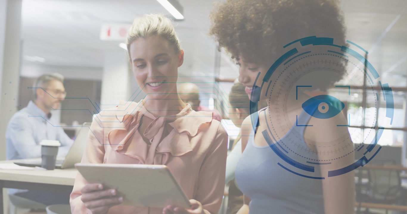 Two women reviewing tablet in office, presenting business data with eye icon and circular HUD