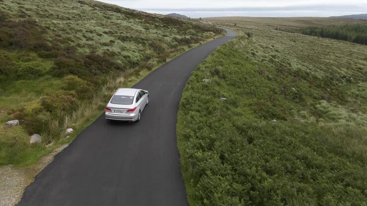 Drone shot of a car driving on a mountain road.