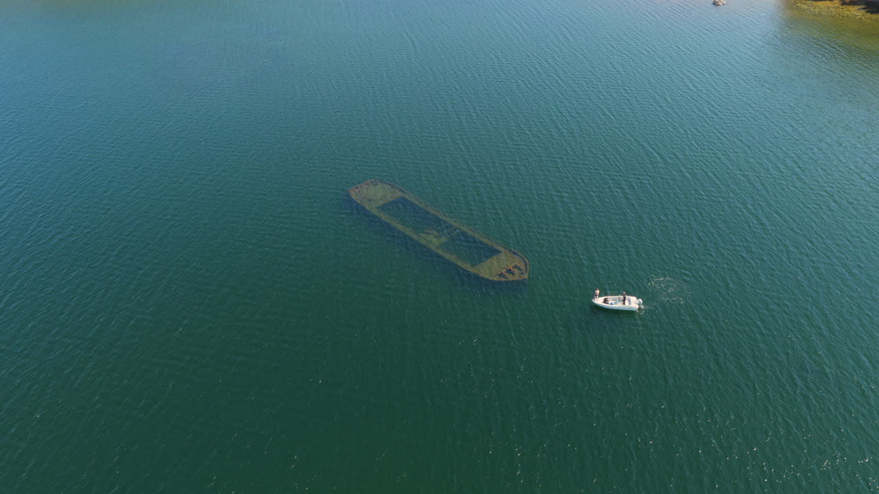 Aerial view orbiting a motorboat arriving at a shipwreck, in Saimaa,, Finland