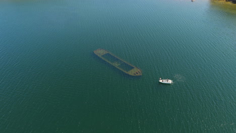 aerial view orbiting a motorboat arriving at a shipwreck, in saimaa,, finland