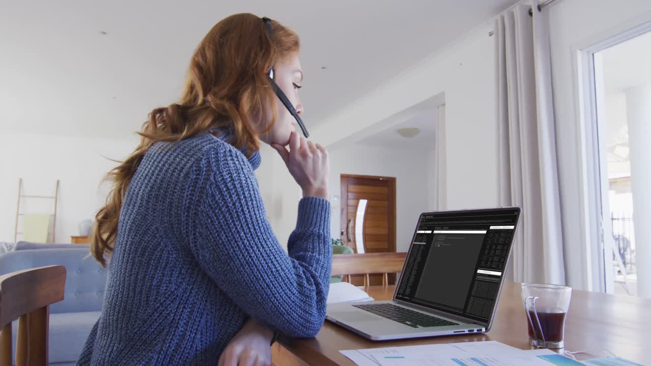 Caucasian woman sitting at desk watching coding data processing on laptop screen