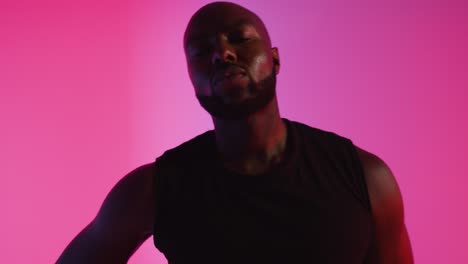 Close-Up-Studio-Portrait-Of-Male-Basketball-Player-Dribbling-And-Bouncing-Ball-Against-Pink-Lit-Background