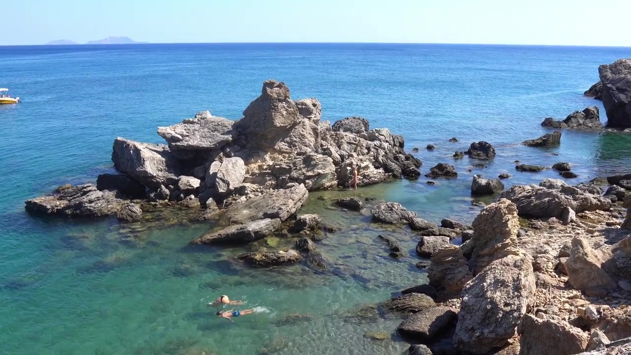 Persone che nuotano in acqua turchese vicino alle rocce in Grecia